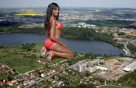 bikini breasts giantess collage mega black_hair long_hair butt swimsuit high_heels buildings kneeling grass lake dark_skin trees looking_at_viewer suburbs red_swim_suit