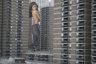 giantess collage city destruction jeans brunette wonderslug looking_at_viewer between_buildings ear_ring carla_ossa
