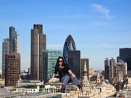 breasts giantess collage city mega black_hair clothed boots sitting london skyscraper sunglasses sky looking_at_viewer rooftop sitting_on_building gherkin