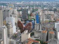 giantess collage city blonde toes barefoot soles lying_down unknown_artist skyscraper looking_at_viewer rooftop_view
