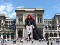 gentle giantess collage long_hair clothed red_hair looking_down standing onlookers sunny cape crucifix outdoor_mall