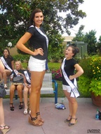 long_hair high_heels smiling legs amazon short_shorts looking_up towering shirt earrings looking_at_viewer hand_on_hips hair__tied_back