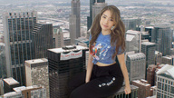 giantess collage city mega long_hair clothed buildings brunette smiling sitting twintails pants outdoors looking_at_viewer docop sitting_on_building sign pokimane